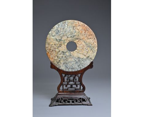 A LARGE CHINESE JADE BI DISC ON WOODEN STAND. The circular jade disc with incised decoration to one side of four Taotie masks