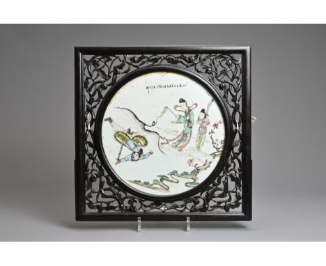 A FRAMED PORCELAIN PLAQUE, EARLY 20TH CENTURY. The circular porcelain tile painted with figures and calligraphy in a square c