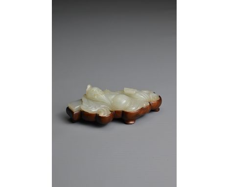 A CHINESE WHITISH PALE CELADON JADE FIGURE OF A SCHOLAR, QING DYNASTY. The bearded figure dressed in robes reclining with his