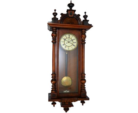 A late 19th century mahogany cased Vienna style wall clock, with arched pediment and turned finales above the enamel dial wit