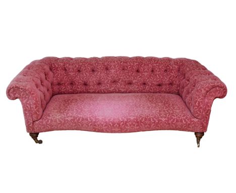 An Edwardian Chesterfield sofa, upholstered in a burgundy Fleur De Lis pattern fabric, buttoned-down with scroll back and sha