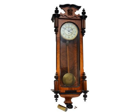 A late 19th century walnut and ebonised Vienna style wall clock, with carved pediment and finials, fully glazed door flanked 