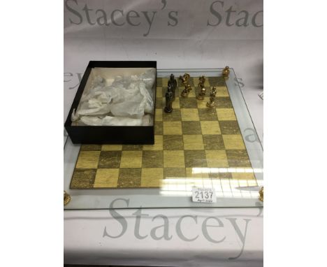 A glass chessboard with silver and gold coloured chess pieces. NO RESERVE