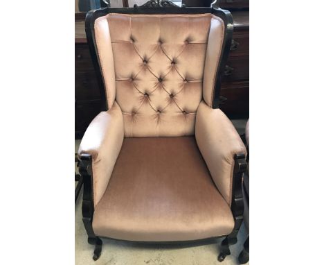 A late Victorian button backed wing chair with dusky pink velvet upholstery. On ceramic castors and with carved detail to top