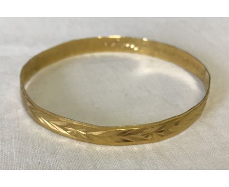 A 22ct gold bangle  with engraved detail. Weight approx. 11.7g.  Shows signs of repair inside and also has an inscription in 