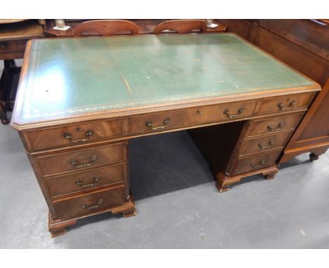 A mahogany partners desk, in George III style, the rectangular top with a green leather insert, canted corners, above an arra