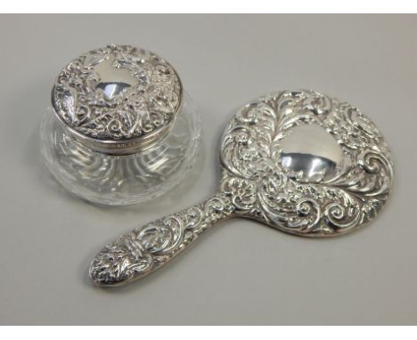 Two silver mounted items, dressing table mirror with embossed decoration and a cut glass powder flask with silver lid, stampe