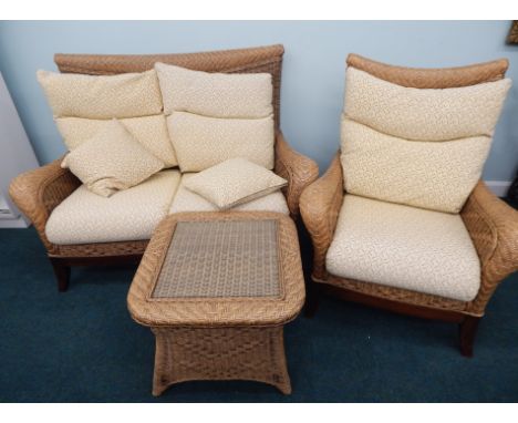 A good quality woven rattan conservatory type suite, comprising two seater sofa, an armchair with loose cushions, on a mahoga