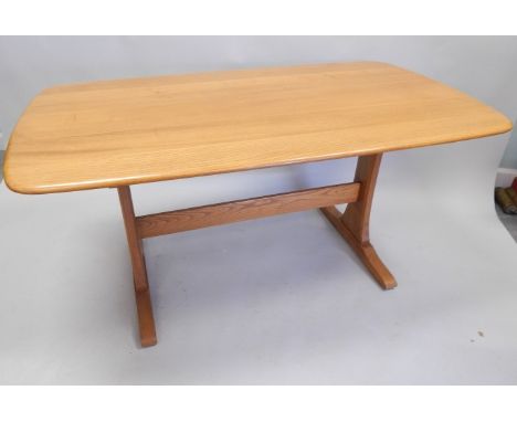 An Ercol type light elm kitchen table, the rectangular top with a shaped edge on plain end supports, with stretcher, the top 