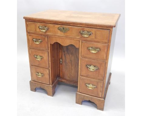 A walnut kneehole desk in mid 18thC style, the rectangular feather banded veneered top, with a moulded edge, above a frieze d