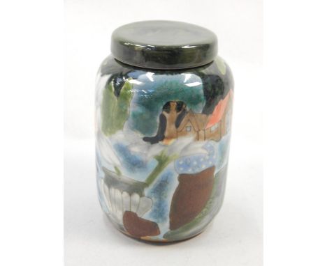 A Cobridge ceramic jar and cover, decorated with a scene of a house, watering can, boots, flowers etc., stamped to underside,