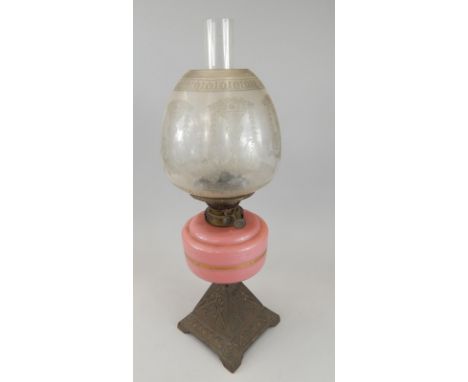 A Victorian oil lamp, with an etched shade, pink tinted reservoir and tapering cast brass base, 59cm high