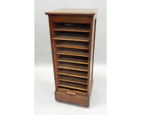 A Lebus oak filing cabinet, with a tambour door, enclosing sliding trays on plinth base, 49cm wide.