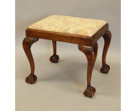 An early 20thC walnut stool, with a padded seat, on cabriole legs, with ball and claw feet.