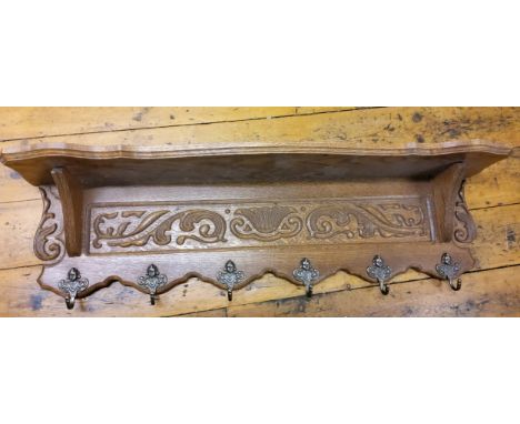 A mid 20th century oak coat hook and shelf, carved with scrolling foliage, 100cm long 