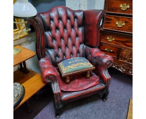 An ox blood red leather Chesterfield wingback armchair, deep button backed; Lord Of The Manor tapestry upholstered footstool 