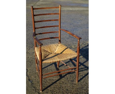 A Gimson design ladder back elbow chair with rush envelope seat, on turned and stretchered supports