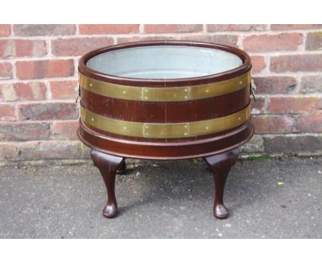 A REPRODUCTION MAHOGANY OVAL WINE COOLER IN THE GEORGIAN STYLE, having modern tin removable liner, with brass banding and lio