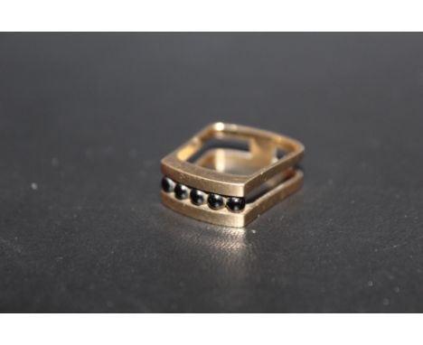A HALLMARKED 9 CARAT GOLD UNUSUAL SHAPED RING, set with five polished black spherical stones in a channel, approx weight 4.9g