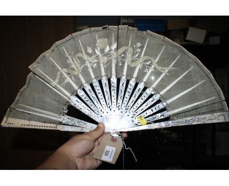 A late 19th Century carved and pierced mother-of-pearl stick fan with painted vane (damages)