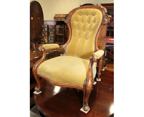 A Victorian mahogany spoon back armchair, button upholstered in a gold velour, on cabriole supports