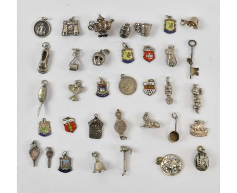 A group of hallmarked silver bracelet charms including binoculars, bell, pan, skull, mug, shoe, teapot, bellows, cherub, poli