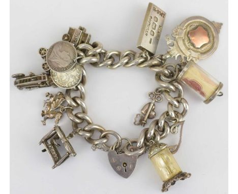A hallmarked silver charm bracelet with eleven charms including coins, clock, fire engine, dragon, with silver heart shaped p