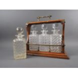 An oak and metal mounted three-decanter tantalus, and one other spirit decanter and stopper