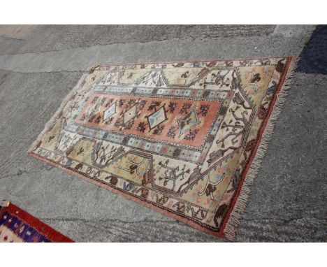 A Kazak style wool pile rug with geometric design on a pink ground and multi-borders on a light ground, 82” x 48” approx