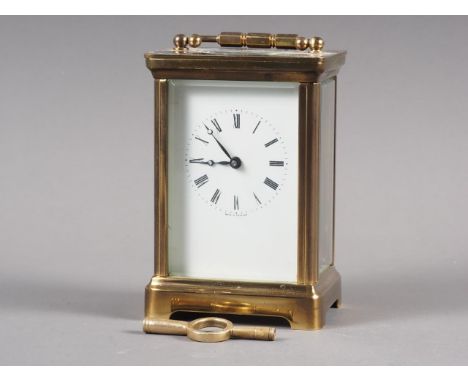 A brass cased carriage clock with white enamel dial and Roman numerals, with key