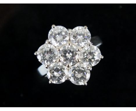 An 18ct white gold seven stone diamond floral cluster ring, designed as a central raised brilliant cut diamond within a surro