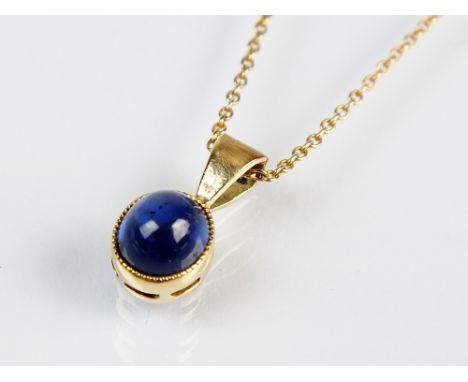 An oval cabochon sapphire pendant, within yellow metal collet mount, measures approx 5.5mm x 4.5mm, suspended from yellow met