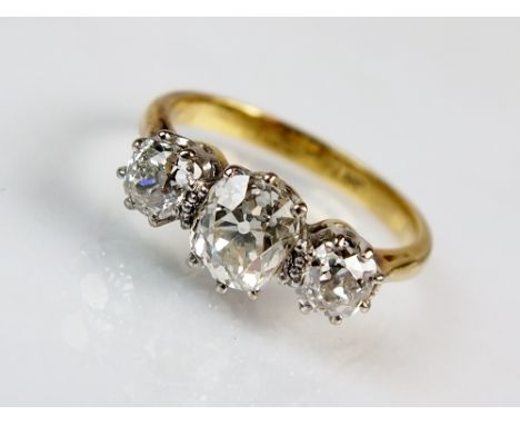 A three stone graduated diamond ring, designed as a central oval old cut diamond flanked to each side by a further old cut di