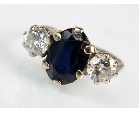 A three stone diamond and sapphire ring, designed as a central oval mixed cut sapphire flanked to each side by a brilliant cu