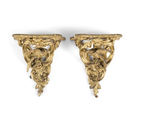 A PAIR OF GEORGE III CARVED GILTWOOD WALL BRACKETS, the carved shaped rectangular shelf supported by a phoenix, perched among