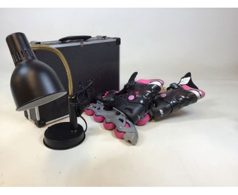 A contemporary adjustable desk lamp together with a pair of in line skates and a hard sided case