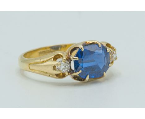 18 carat gold synthetic sapphire dress ring. Stone size 6mm x 4mm set with diamonds on the shoulders. Ring size 6.75