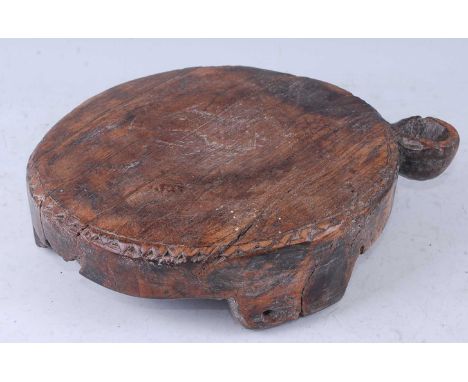 A teak chapati board, of circular form within a carved border and with water aperture, raised on plain tripod supports, South