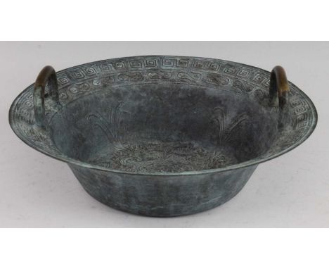 * A Chinese copper alloy twin handled basin, the interior relief decorated with celestial dragons encircling a central seal, 