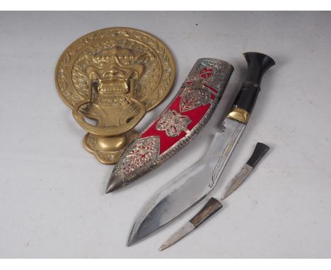 A Chinese brass door knocker, formed as a mask, 6 1/2" wide x 9 1/4" high, and a kukri, in white metal and fabric scabbard 