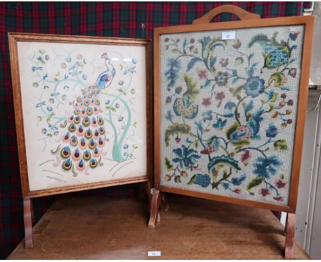 An early 20th century oak framed fire screen embroidered with the image of a peacock and an other oak framed tapestry fire sc