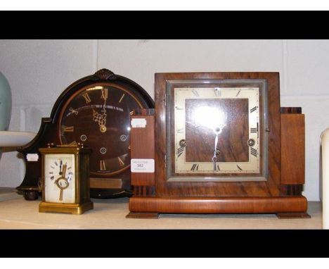 A brass carriage clock in the company of two mantel clocks 
