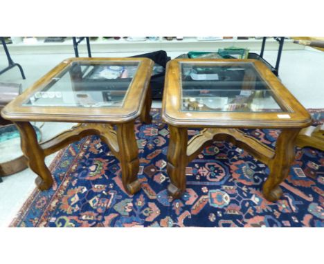 A pair of modern oak finished lamp tables, each top set with a glass panel, raised on serpentine legs, united by cross stretc
