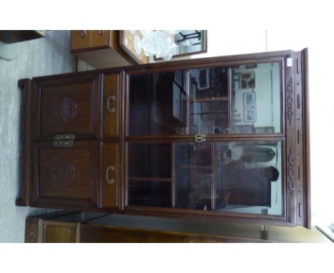 A mid 20thC Chinese rosewood netsuke cabinet, the cornice with a carved and moulded ornament, over two glazed doors, enclosin