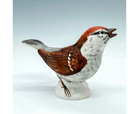 Handpainted bird with brown and gray coloration. Figurine depicts bird speaking while standing on white floral base. Goebel b