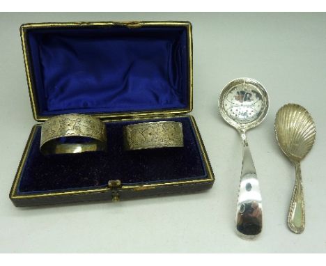 A silver caddy spoon, a pair of silver napkin rings, cased and a silver strainer, weight 69g