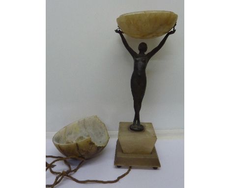 A spelter Art Deco table lamp in the form of a nude female figure holding a globe, with alabaster base and a light shade, sha