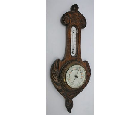 A mid 20th Century English made oak arts and craft carved style Aneroid Barometer no. 547355, brass mounted dial, 47cm high