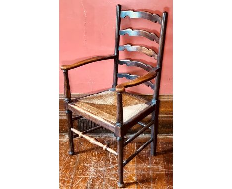 An Arts &amp; Crafts ladder back armchair, circa 1920, scroll arms, rush seat, ring turned legs, baluster turned front stretc