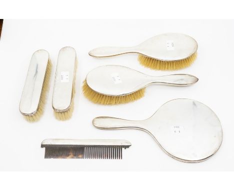 A hand mirror, a pair of brushes and a comb with plain silver mounts, London 1918 and a further pair of brushes, Birmingham m